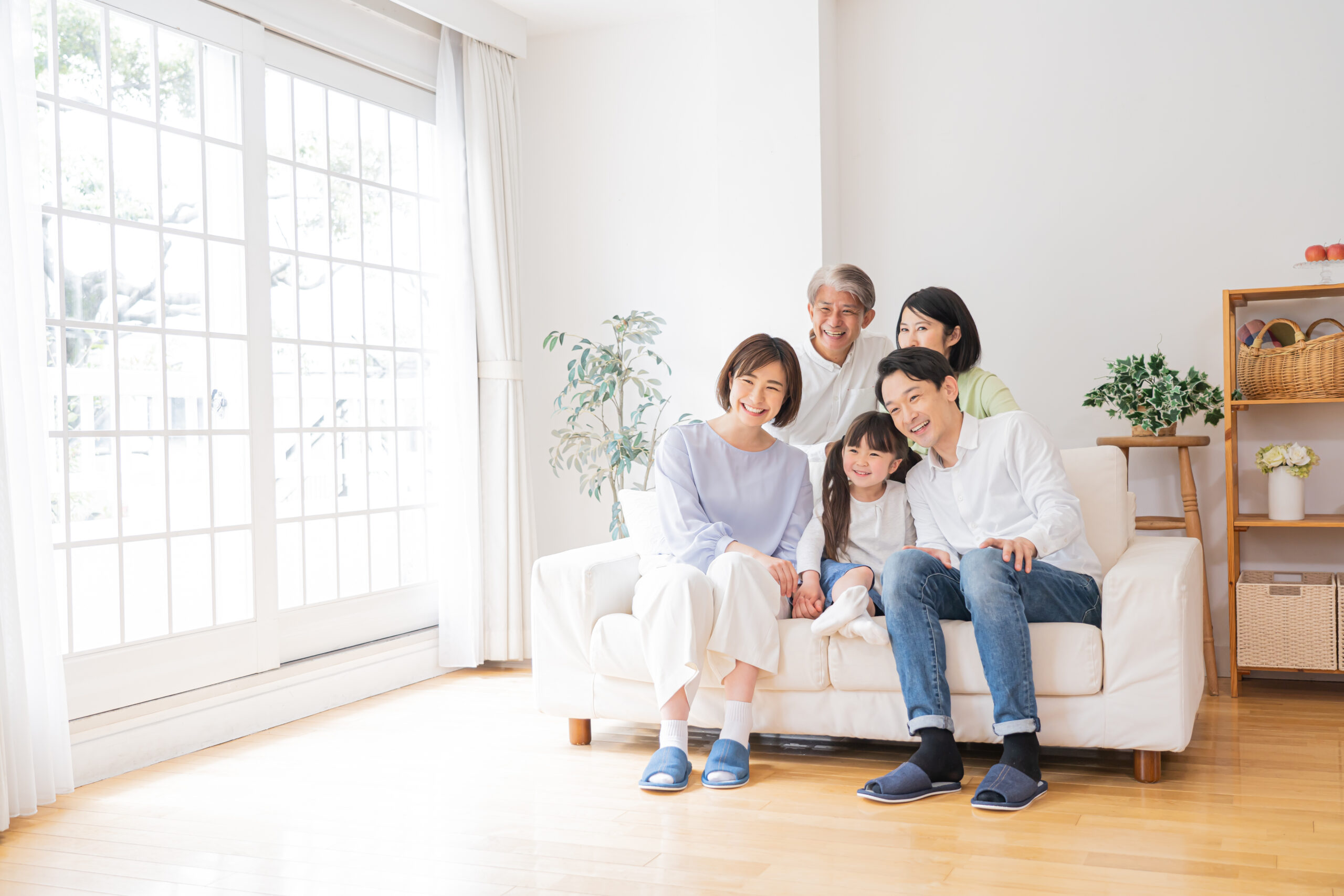 床に座りくつろぐ祖父母・両親・子どもの三世代家族