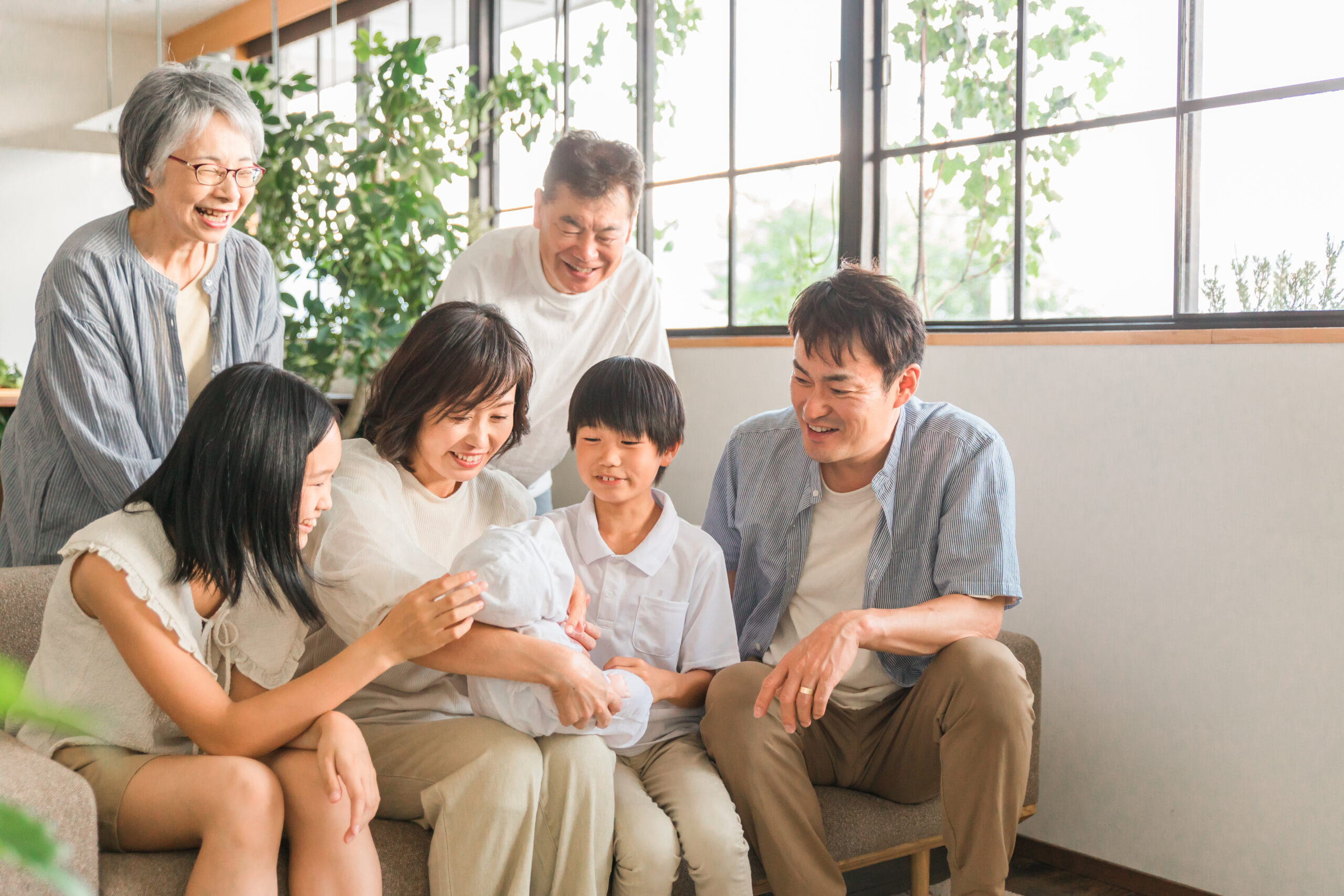 三世代が窓辺に並んで座り、話している様子
