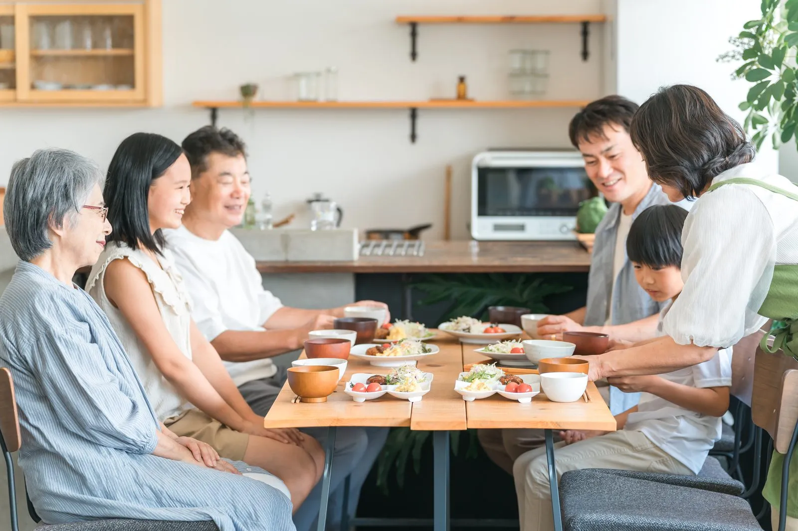 三世代の家族がひとつの食卓を囲んで食事をする様子